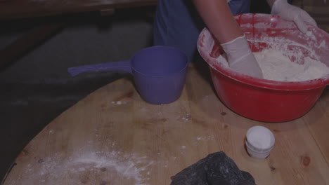 panadero mezclando masa en un tazón grande sobre una mesa de madera, cocinando albóndigas georgianas khinkali - ángulo alto