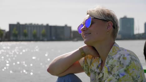 confident young woman soaks in the summer sun, bay and city in the background.