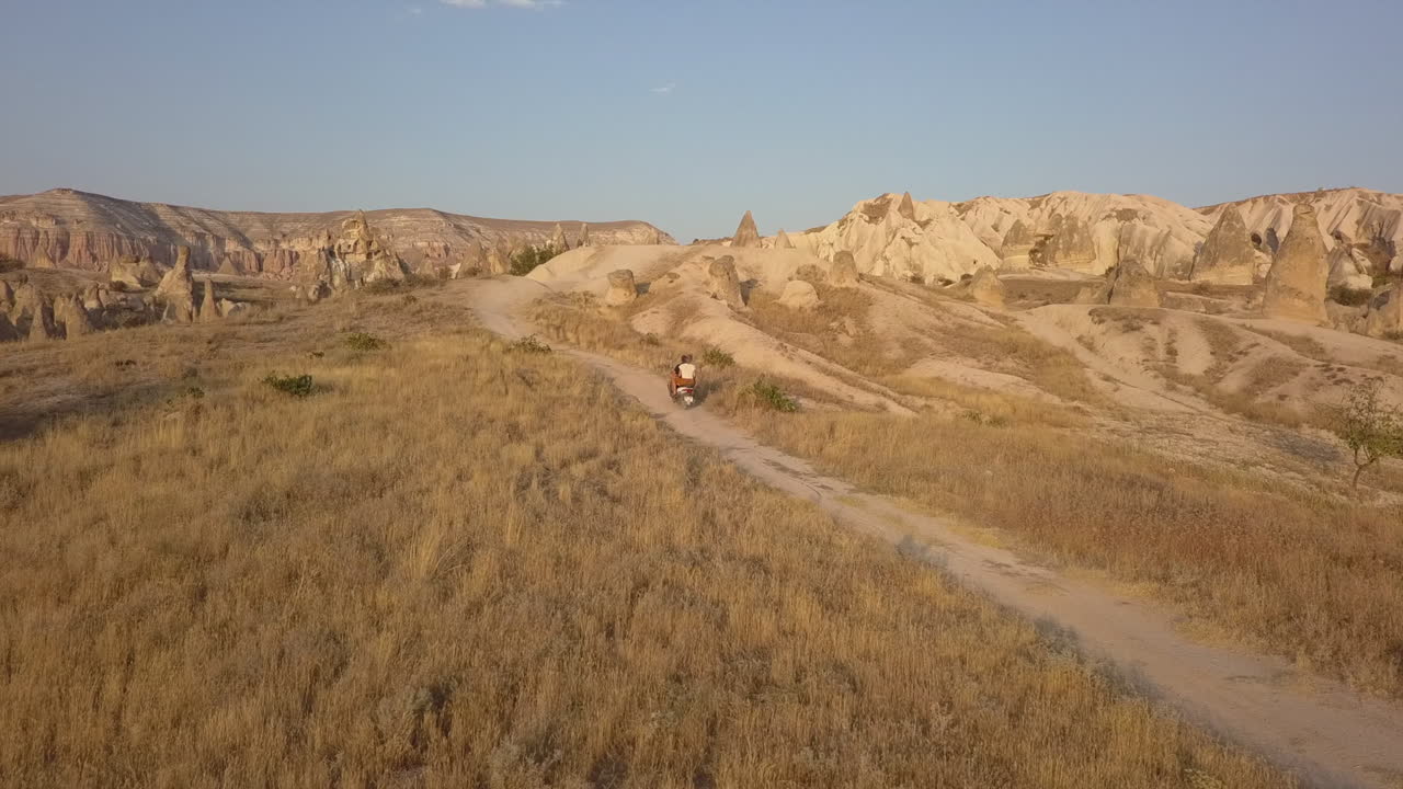 luz dorada del amanecer aéreo como pareja en moto hacia las tierras baldías de hoodoo