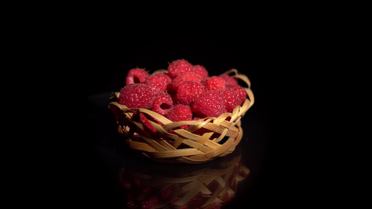 검은 바탕에 작은 wicker 바구니에 회전 빨간 라즈베리.