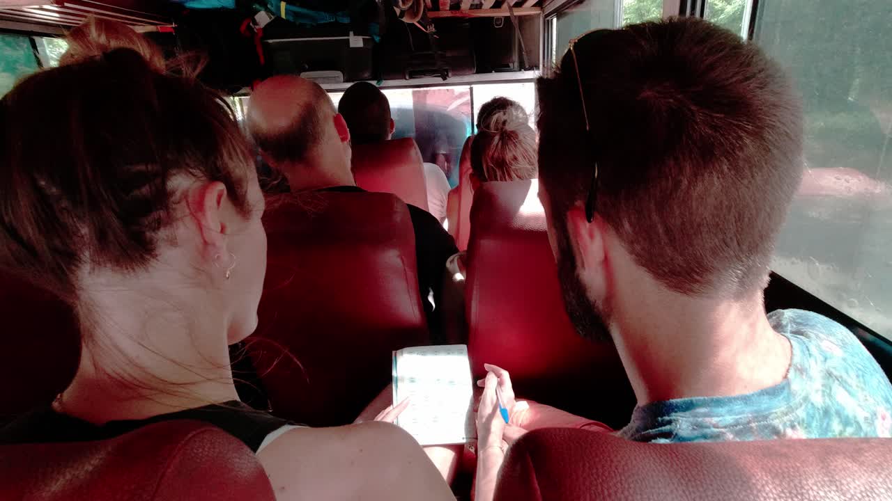 Couple playing crossword puzzle while travelling in an old truck in Cuba