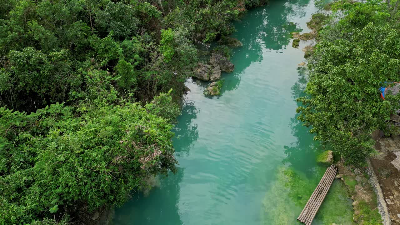 Movimento aereo della camera che segue il fiume turchese e sinuoso mentre scorre attraverso la fitta foresta tropicale verso le cascate di Bolinao a Bolinao, Pangasinan, Filippine