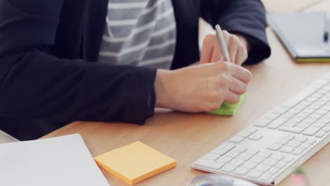 businesswoman using computer and taking notes