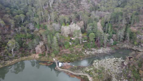 vista aérea de 4k de un desfiladero con senderos, un puente colgante y una pequeña cascada en un parque nacional australiano