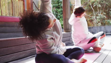 Mixed-race-couple-performing-stretching-exercise-together-at-vacation-home