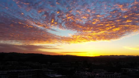 Colorful-golden-sunset-over-Highway-Route-101-in-Southern-California-with-the-landscape-in-silhouette---sliding-aerial-view