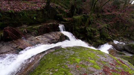 Rocas-Del-Bosque-Cubierto-De-Musgo-Con-Cascada-De-Arroyo-Que-Fluye---Antena