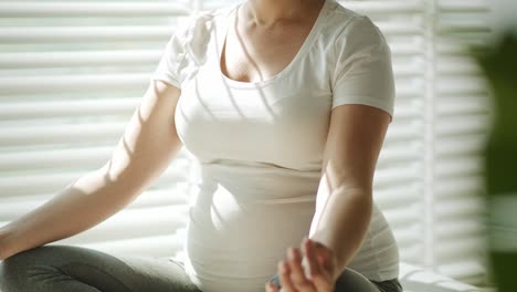 Handheld-video-of-pregnant-woman-meditation-in-the-sunbeams.