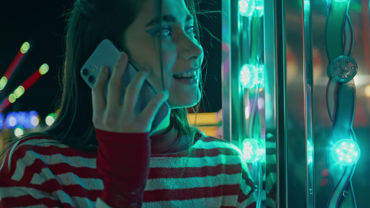 네온 조명 속의 셀에서 얘기하는 기쁜 소녀. 가까운 사진. 행복한 십대 친구에게 손을 흔들고