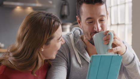 Pareja-Usando-Tableta-Digital-En-Casa-Divirtiéndose-Tomando-Café