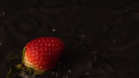 Strawberry-falling-on-wet-black-surface