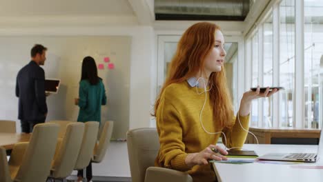 female graphic designer talking on mobile phone at desk 4k