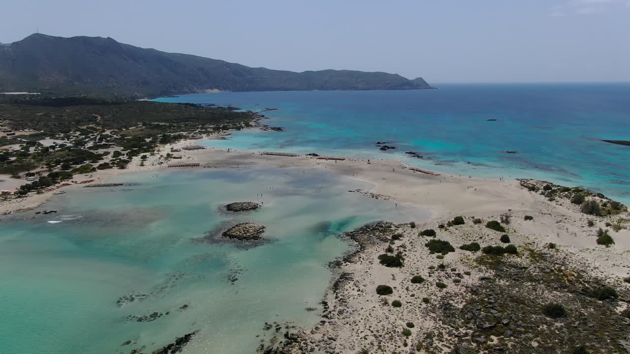 Turquoise colored lagoon at Elafonissi Beach in Crete Greece with rocky shores, Aerial dolly out shot
