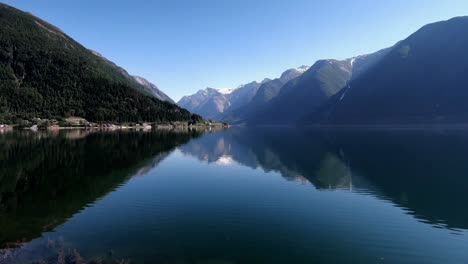 a calm reflective fjord in norway with trees and mountains