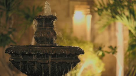 water fountain in courtyard in evening with bokeh wall lights in background