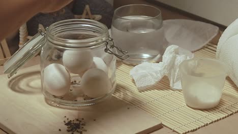 wiping eggs before putting it in a mason jar and adding cracked pepper to add flavor to a classic traditional salted eggs