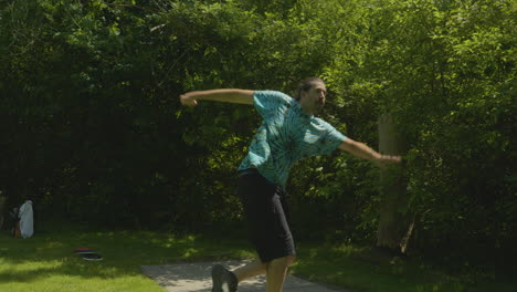 a man prepares to throw from the tee during a disc golf game, set in a densely wooded area, highlighting the sport's challenging environments