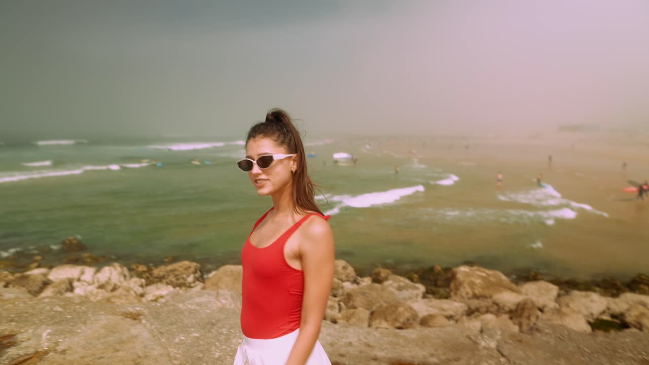 Young Woman in Red Swimsuit Walking on a Rocky Beach