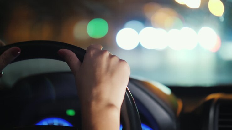 Die Hand einer Frau trommelte nervös auf das Lenkrad des Autos. Steht im Stau. Unsichere Fahrerin.