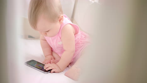 infant girl with mobile sitting in cot. baby watching kid cartoon