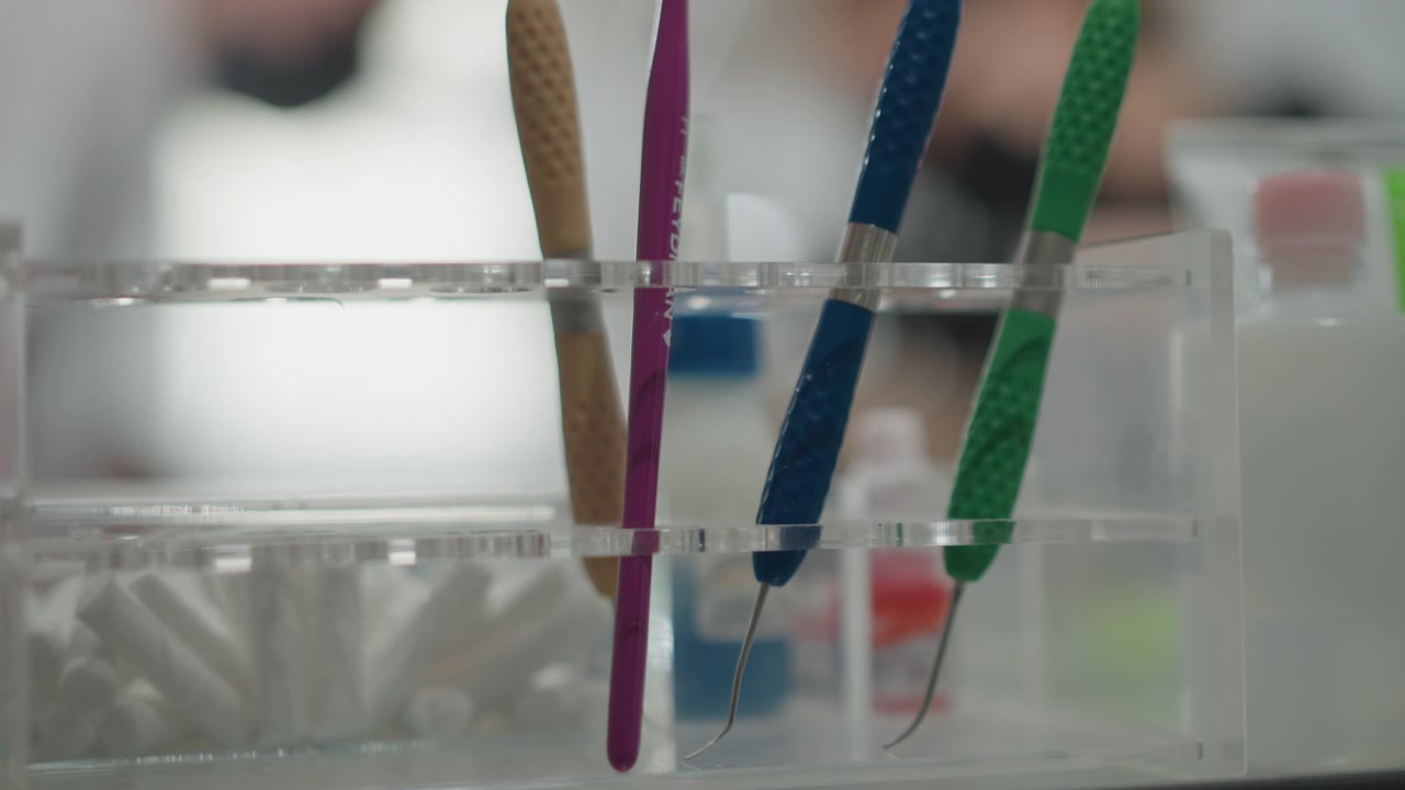 Close up of dental tools including orthodontic instruments in clear plastic organizer with soft lighting. Tools are stationary showing various colors and textures against out of focus