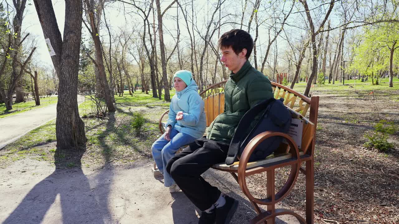 Bambino e bambina seduti su una panchina in un parco soleggiato