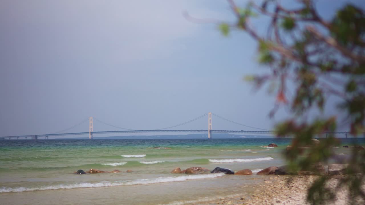 Wide Panning Shot of Mackinac Bridge in Michigan with Beach and Waves in Foreground