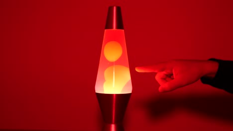 White-male-hand-poking-a-red-lava-lamp-in-slow-motion