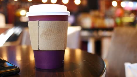 a purple coffee cup on a wooden table in a cafe