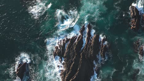 ocean waves crashing over rocky cliffs, rough sea water, drone top down view