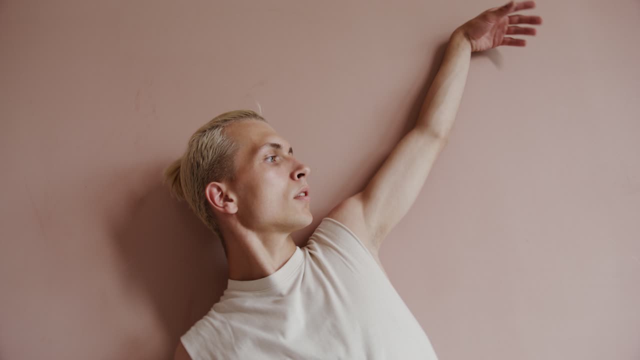 мужчина практикует йогу в студии с розовой стеной