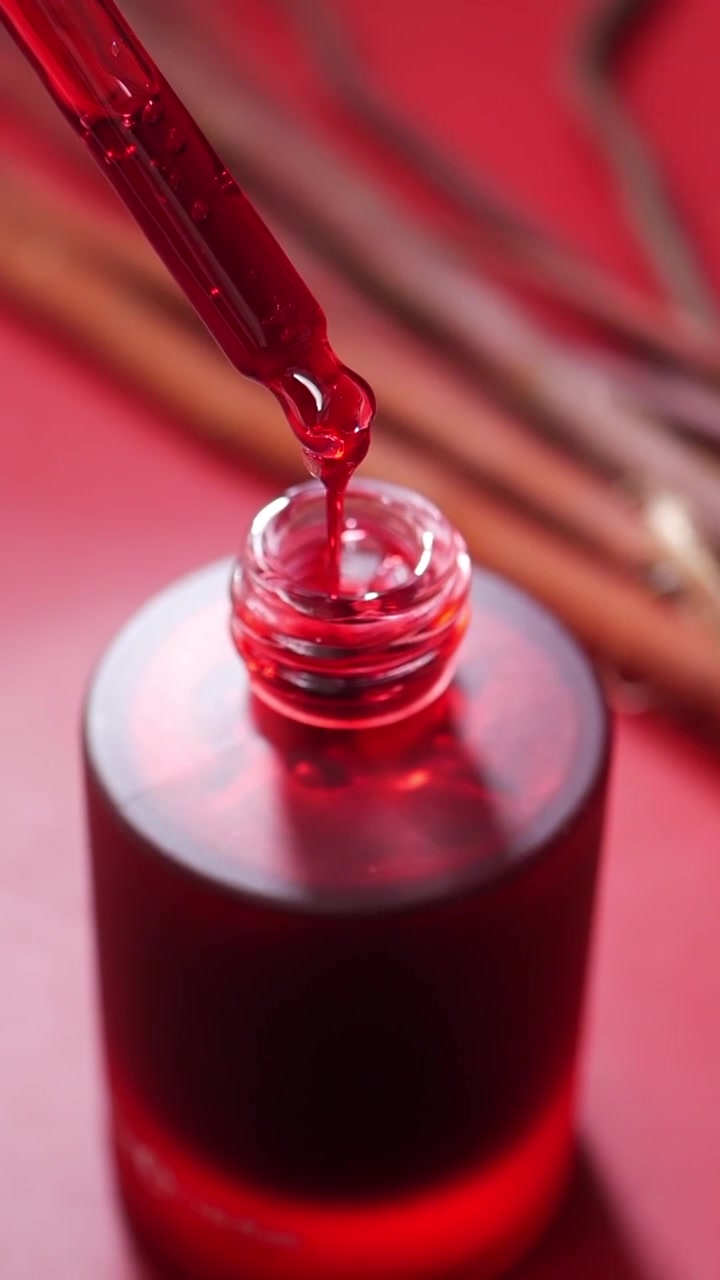 Red Serum Dropping from Pipette into Glass Bottle
