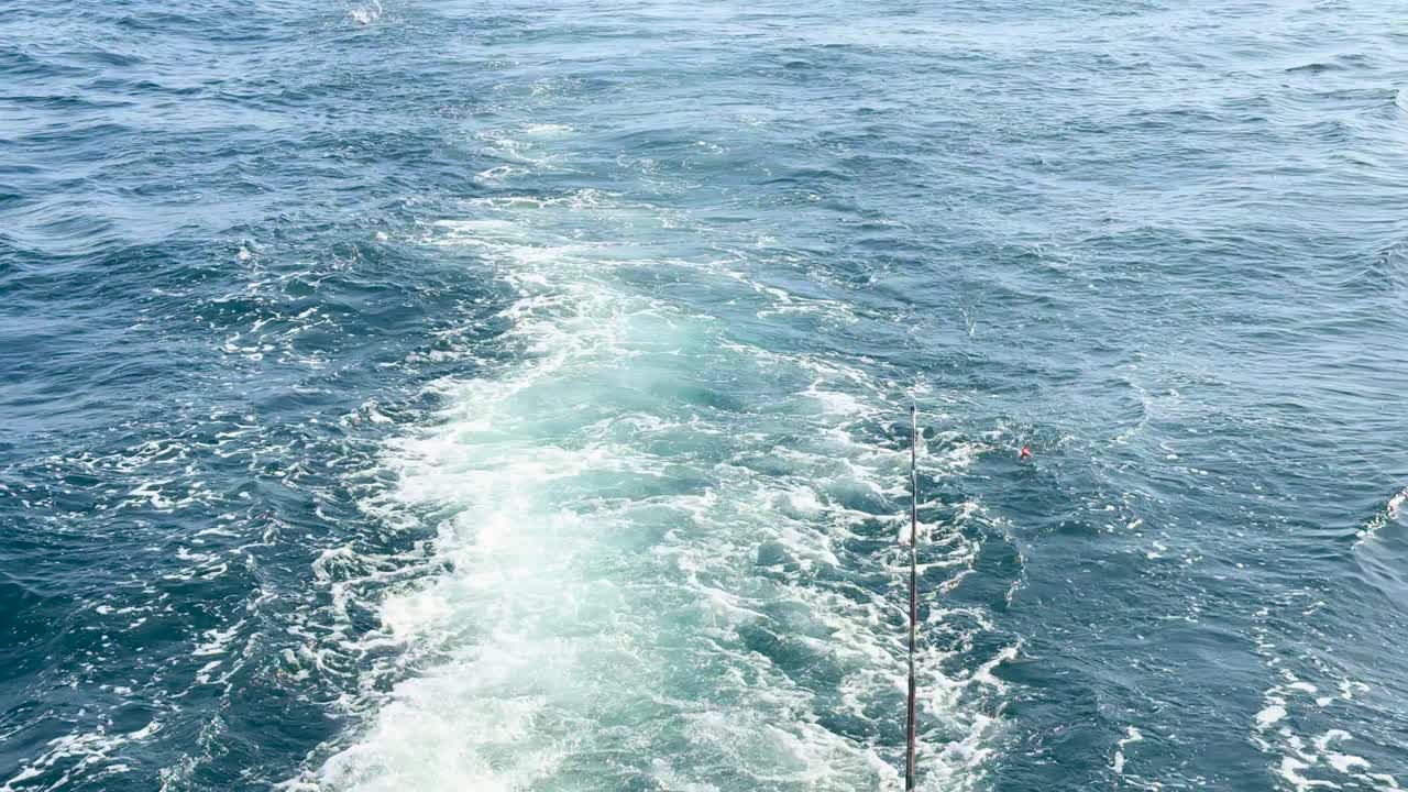 A catamaran sails through Phuket's serene ocean, captured in bright daylight with gentle waves and a clear sky
