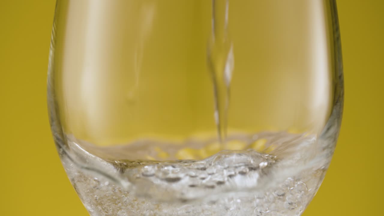 Versando acqua frizzante in un bicchiere da vino, acqua con bollicine.