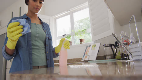 video of happy biracial woman cleaning kitchen