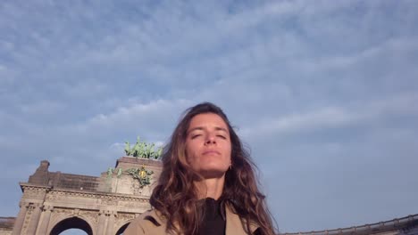 woman stands in front of cinquantenaire arch looking upward