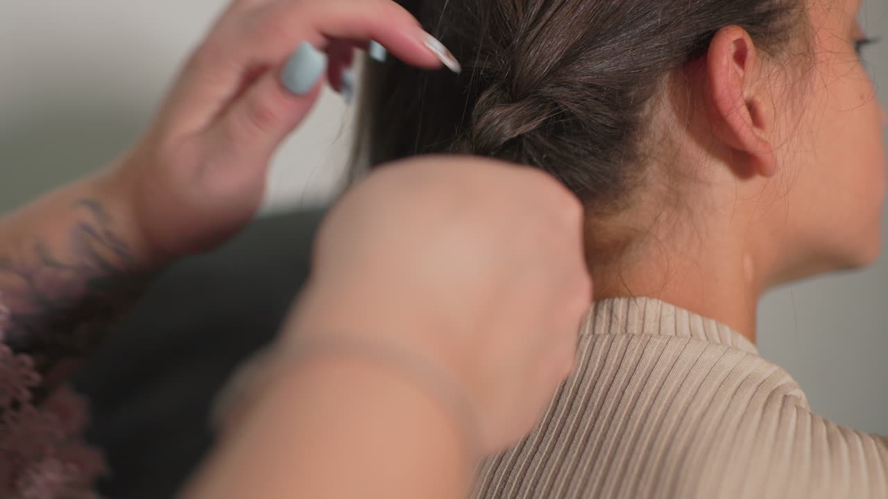 Nanny braiding girl’s hair, close-up shot of focused hands, gentle grooming, child relaxed, calm atmosphere, soft lighting, personal care moment, cozy indoor environment, loving connection