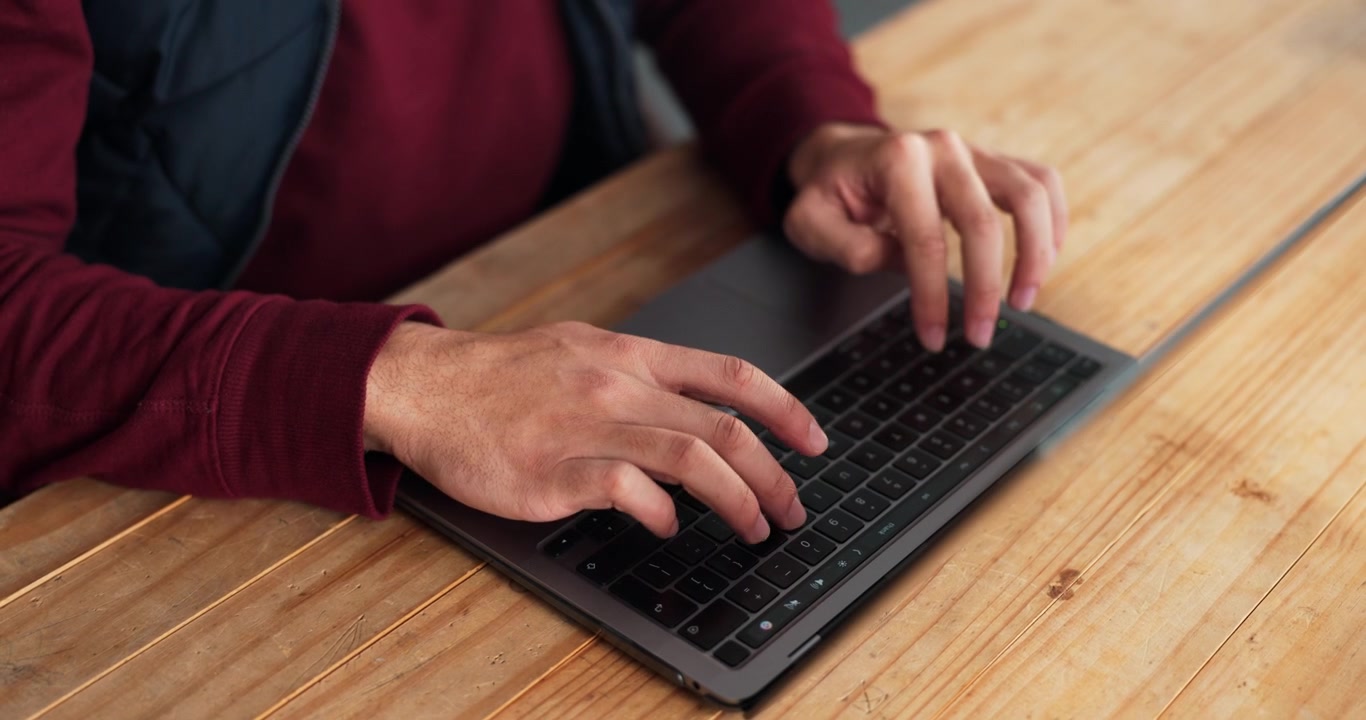 Person Typing on Laptop Keyboard at Wooden Desk