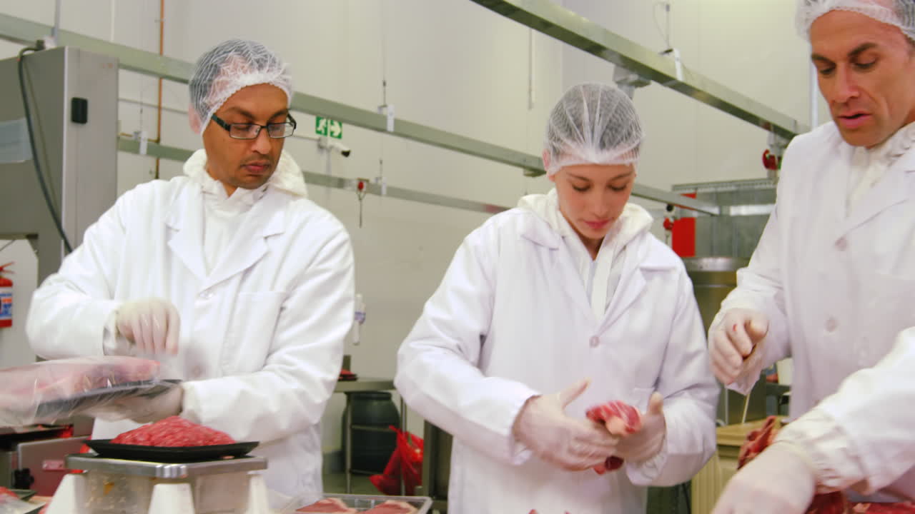Butchers packing and checking the weight of meat at meat factory