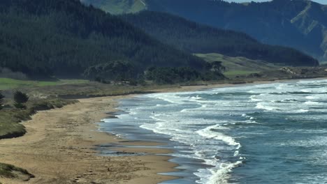 Ocean-Beach-with-waves-breaking-on-shore-in-Hawkes-Bay,-NZ,-drone-shot