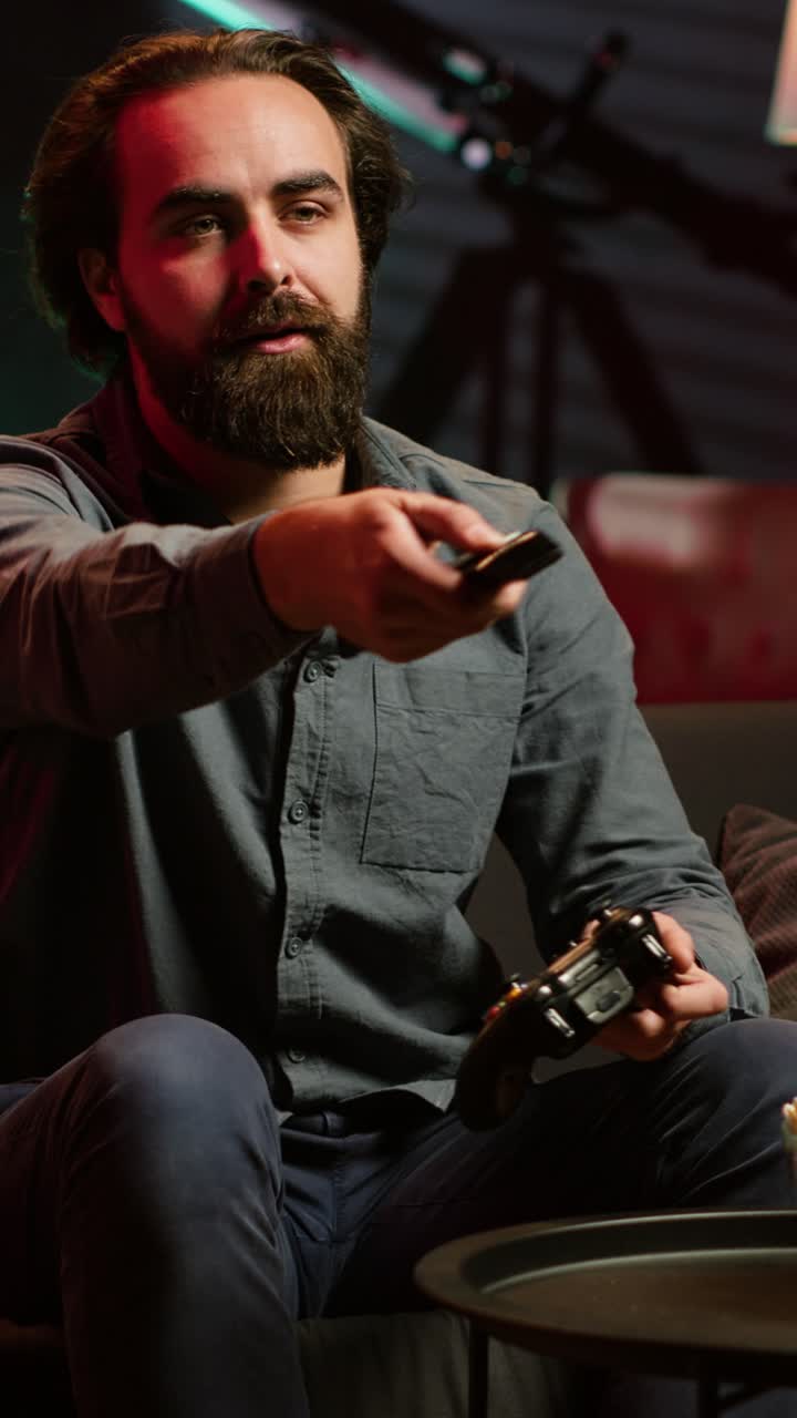 Vertical video Gamer on couch in apartment playing videogame with controller