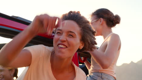 retrato de amigas riendo inclinándose por las ventanas del coche en un viaje por carretera