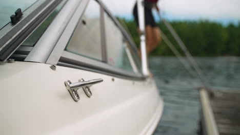 defocused view of a woman wearing a life jacket as she steps out of a boat and onto a dock