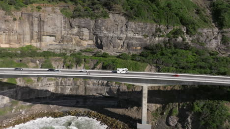 Drone-following-shot-of-campervan-driving-on-famous-Sea-Cliff-Bridge-in-Victoria,-Australia