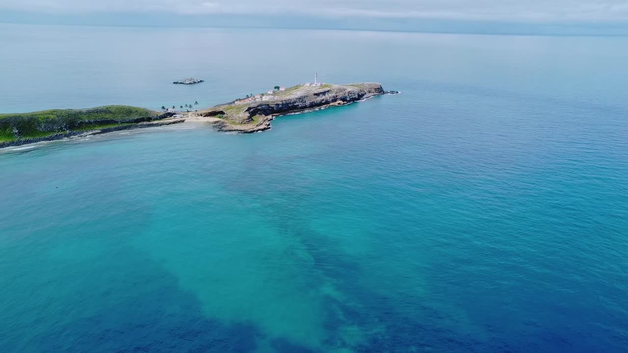 Arcipelago di Abrolhos vicino a Caravelas, Bahia, Brasile, con una bassa isola vulcanica e una piattaforma di barriera corallina circostante nelle limpide acque dell'Atlantico meridionale all'interno di un parco nazionale marino, ripresa aerea con drone in avanti.