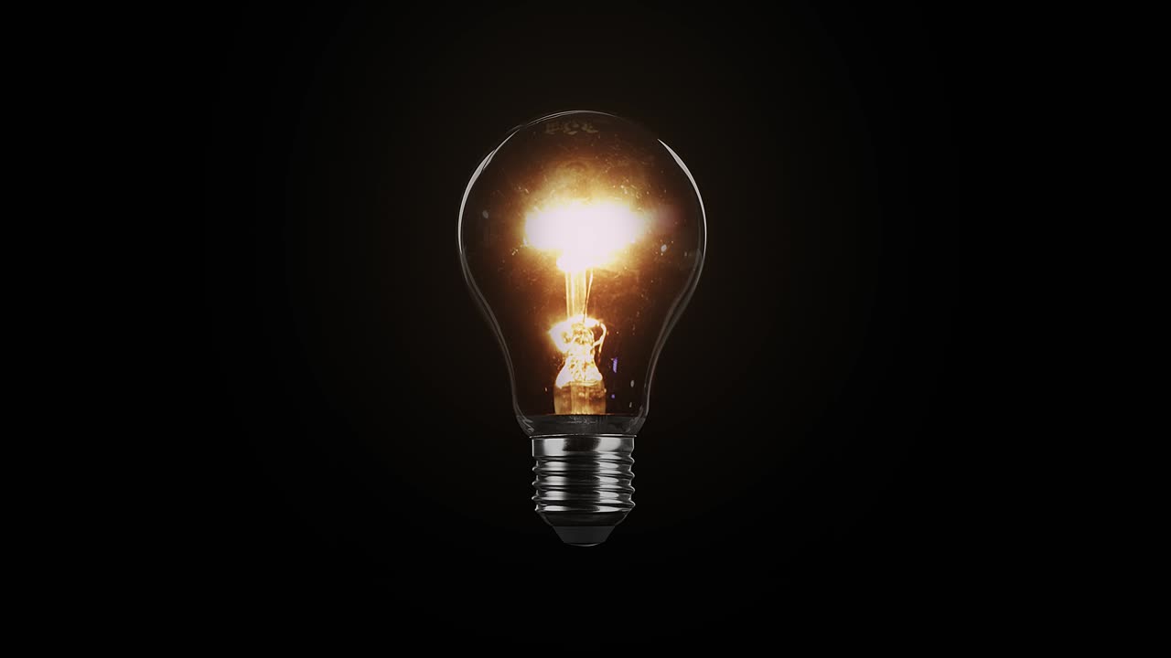 Tungsten light bulb isolated on black background. Glass and metal base. Lights up brightly with a blink and fades out. Loop video in 4K resolution