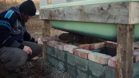 The-Man-is-Positioning-the-Bricks-Beneath-the-DIY-Hot-Tub---Close-Up