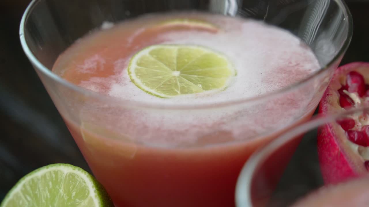 Shot of Creating a pomegranate cocktail concoction juicing and using fresh ingredients and pomegranate seeds