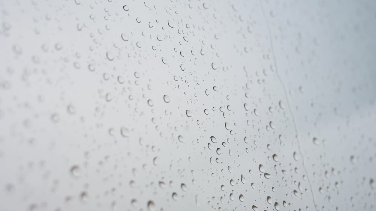 una vista estrecha de las fuertes gotas de lluvia se ve a través de un vidrio de la ventana