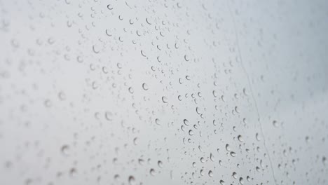 a narroe view of heavy rain drops is seen through a window glass